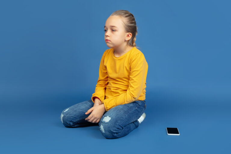 portrait-sad-little-girl-sitting-isolated-blue-background